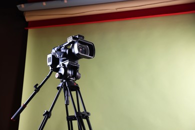 Modern video camera with tripod in studio, low angle view. Space for text