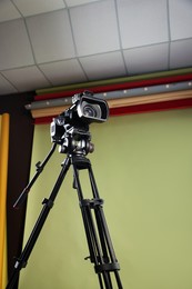 Modern video camera with tripod in studio, low angle view