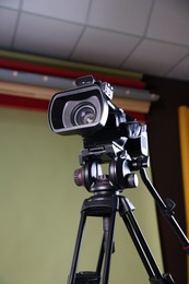 Modern video camera with tripod in studio, low angle view