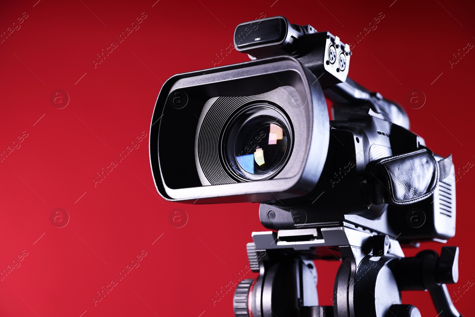 Photo of Modern video camera on red background, closeup. Space for text