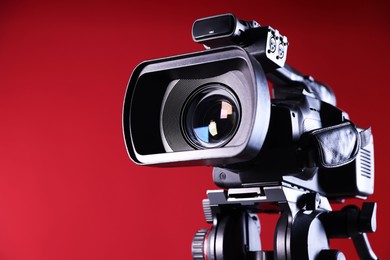 Modern video camera on red background, closeup. Space for text