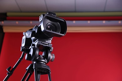 Photo of Modern video camera with tripod in stylish studio, space for text