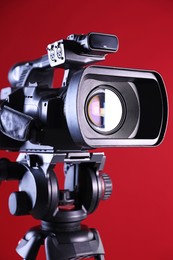 Modern video camera on red background, closeup