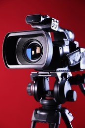 Modern video camera on red background, closeup