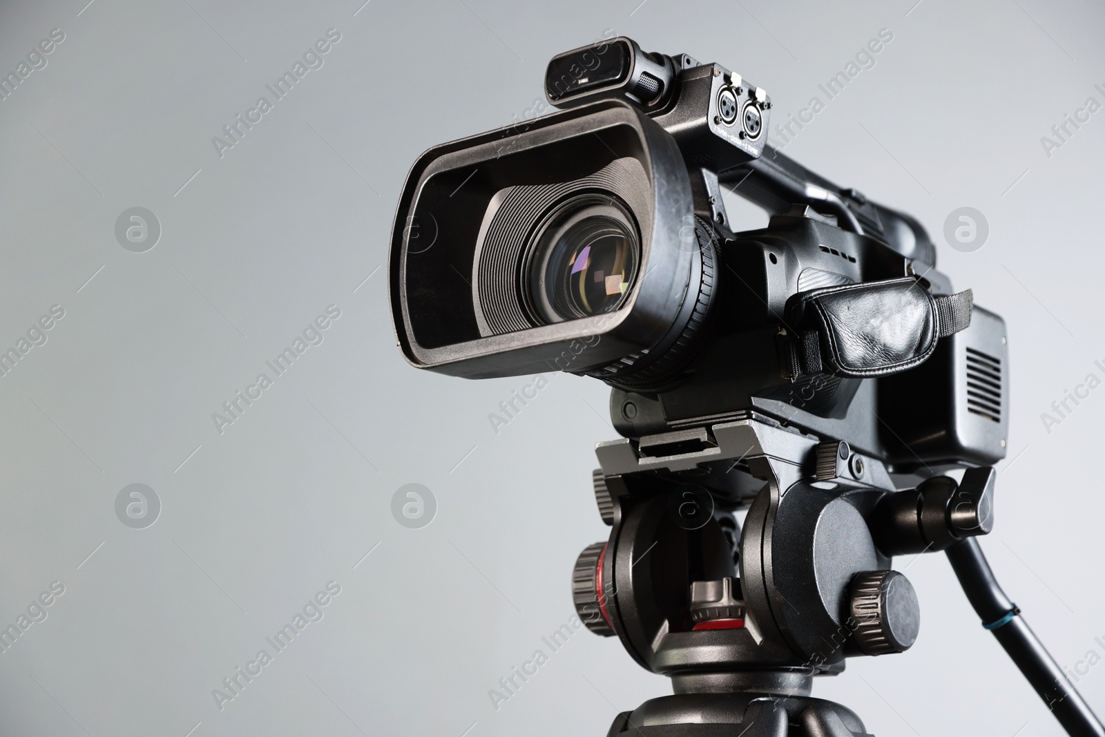 Photo of Modern video camera on light grey background, closeup. Space for text