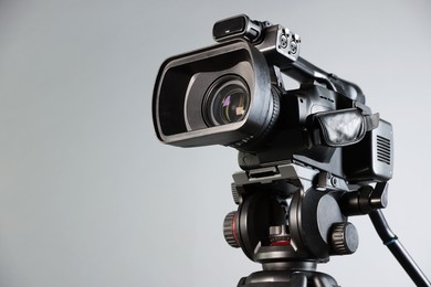 Modern video camera on light grey background, closeup. Space for text