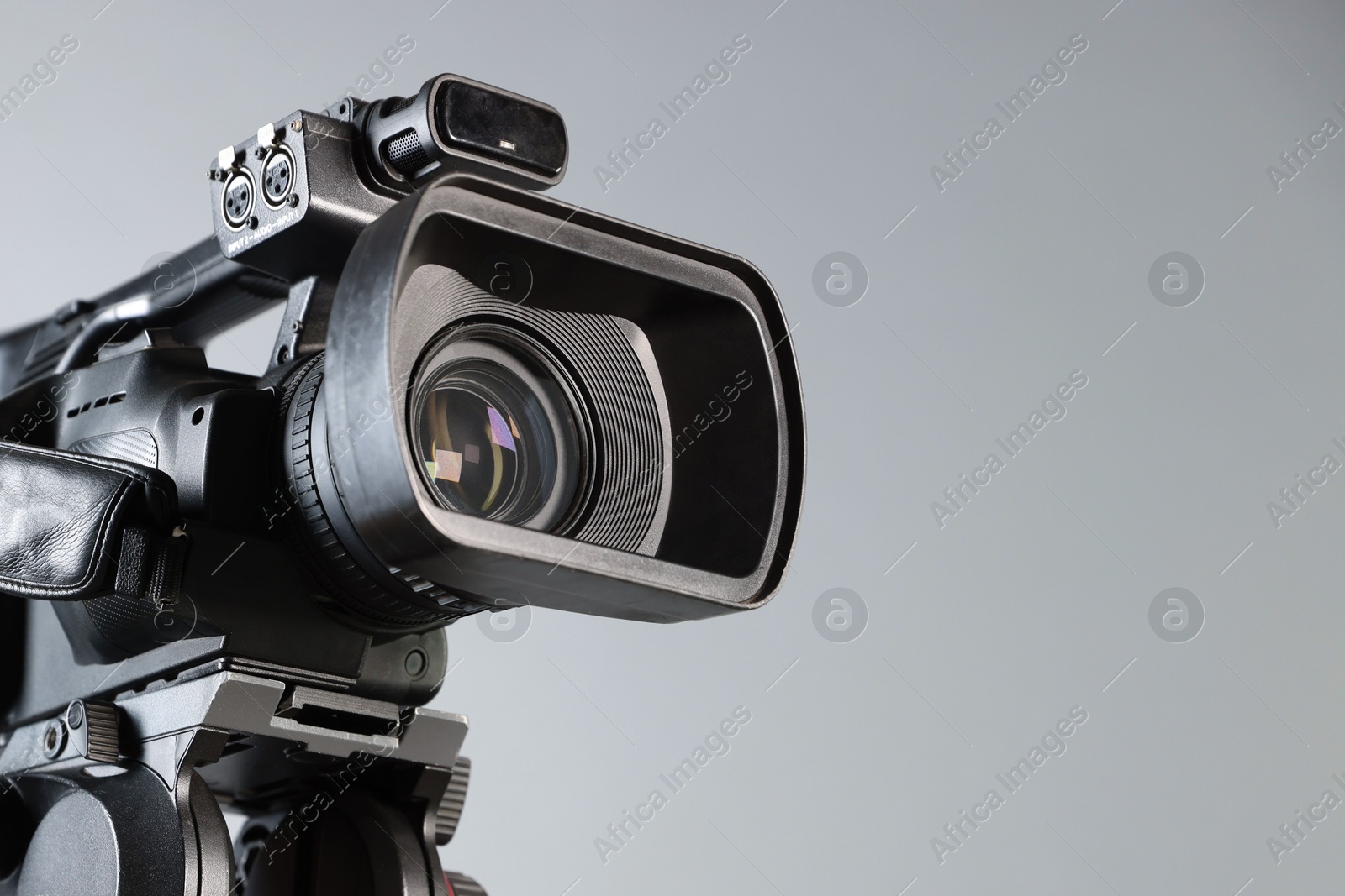 Photo of Modern video camera on light grey background, closeup. Space for text