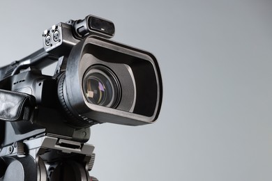 Photo of Modern video camera on light grey background, closeup. Space for text