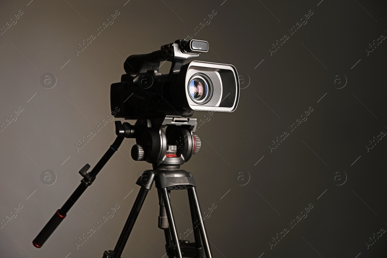 Photo of Modern video camera with tripod on grey background