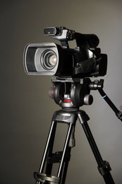 Photo of Modern video camera with tripod on grey background