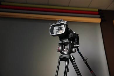 Photo of Modern video camera with tripod in studio, space for text