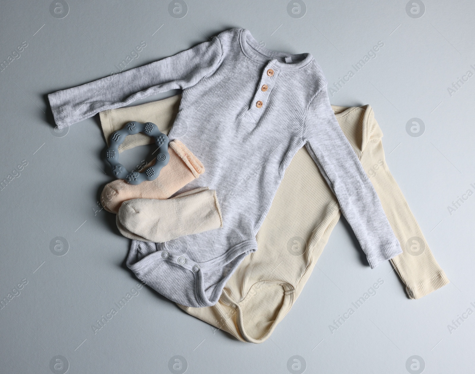 Photo of Baby clothes and teether on light grey background, flat lay