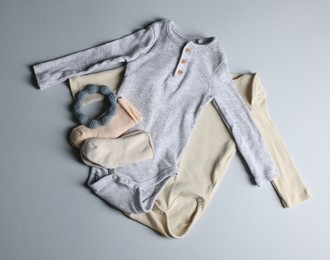 Photo of Baby clothes and teether on light grey background, flat lay