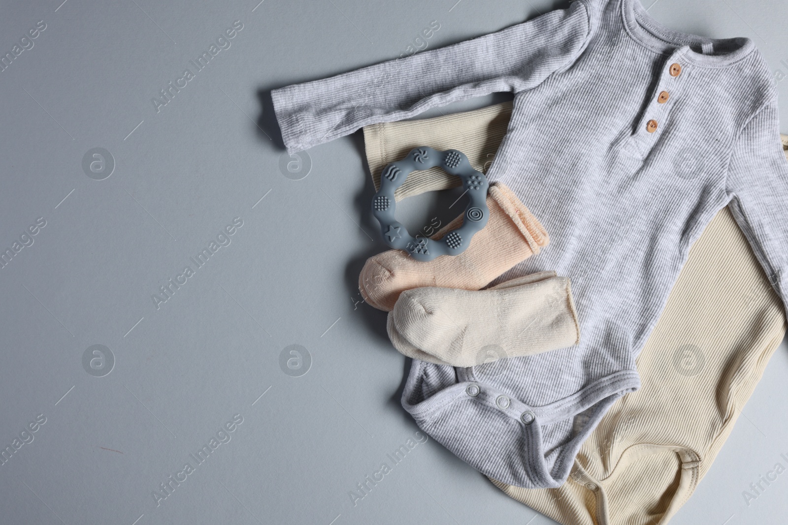 Photo of Baby clothes and teether on light grey background, flat lay. Space for text