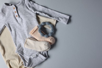 Baby clothes and teether on light grey background, flat lay. Space for text