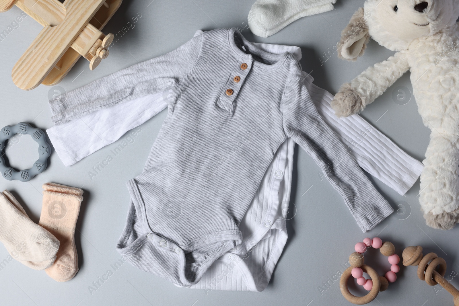 Photo of Baby clothes, toys and teether on light grey background, flat lay