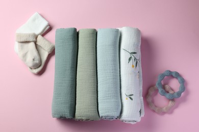 Rolled baby blankets, teethers and socks on pink background, flat lay