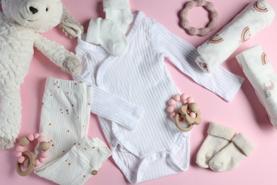 Photo of Baby clothes, toys and teether on pink background, flat lay