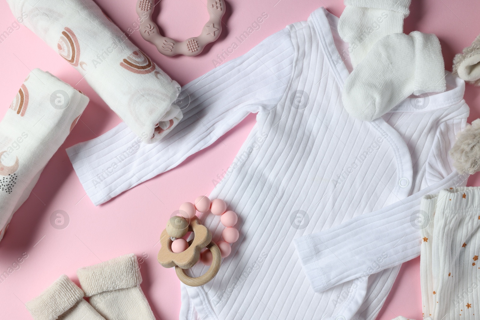 Photo of Baby clothes, toys and teether on pink background, flat lay