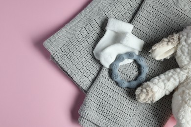 Towel, baby socks, teether and toy on pink background, flat lay