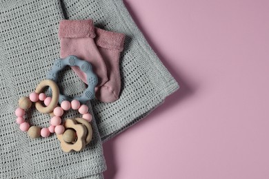 Towel, baby socks, teether and toys on pink background, flat lay. Space for text