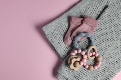 Photo of Towel, baby socks, teether and toys on pink background, flat lay. Space for text