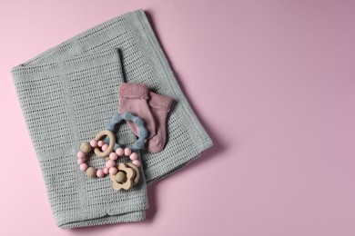 Towel, baby socks, teether and toys on pink background, flat lay. Space for text