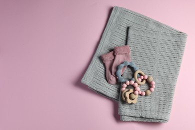 Towel, baby socks, teether and toys on pink background, flat lay. Space for text