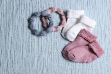 Photo of Baby socks and teethers on gray blanket, flat lay