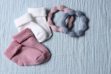 Baby socks and teethers on gray blanket, flat lay