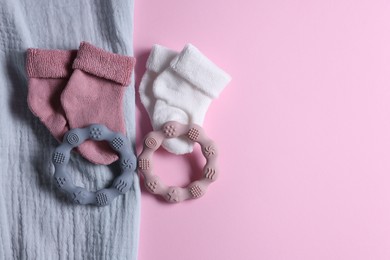 Baby blanket, socks and teethers on pink background, flat lay. Space for text