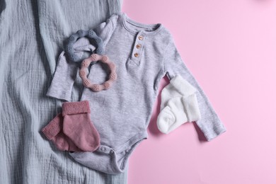 Photo of Baby clothes, blanket and teethers on pink background, flat lay