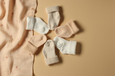 Photo of Baby blanket and socks on beige background, flat lay