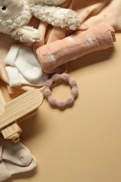 Photo of Baby blankets, toys, socks and teether on beige background, flat lay