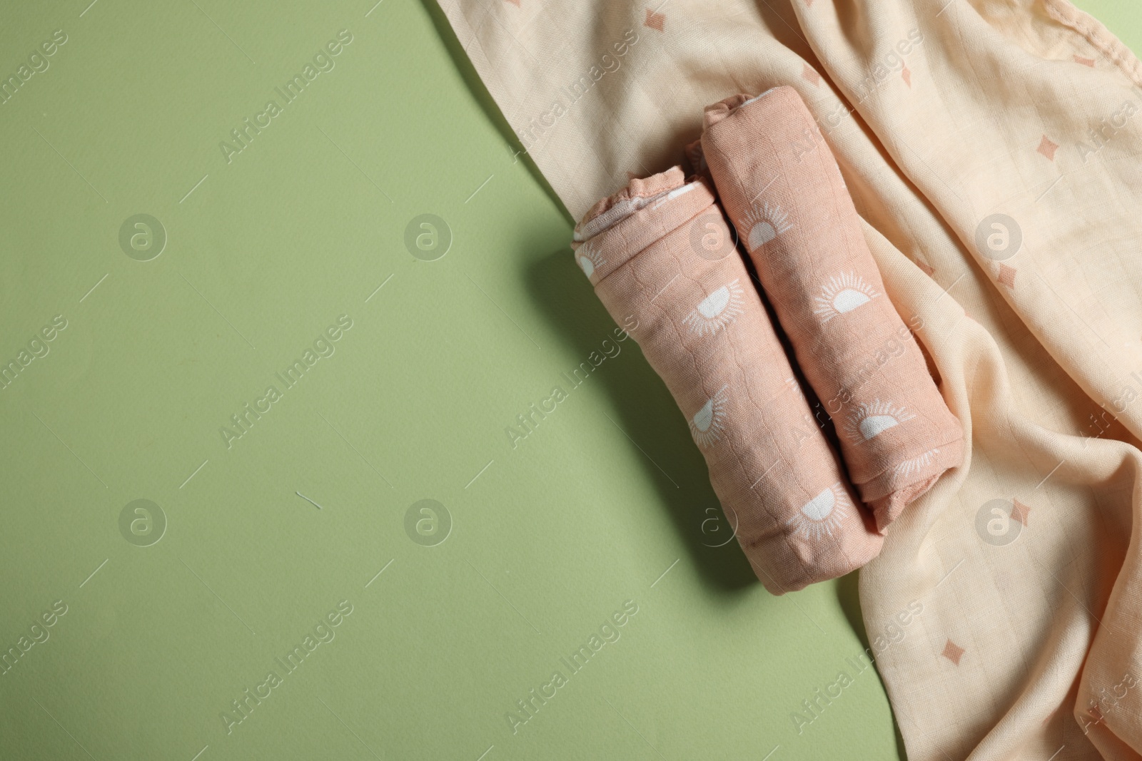 Photo of Rolled baby blankets on light green background, flat lay. Space for text