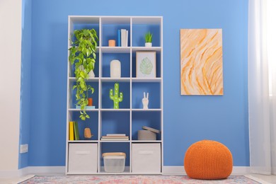 Photo of Shelving unit with decor near blue wall