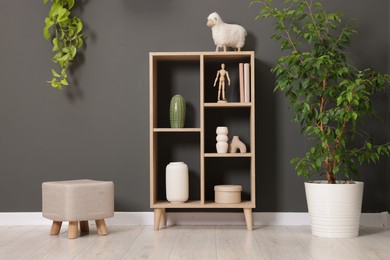 Photo of Shelving unit with different decor and pouf near grey wall indoors