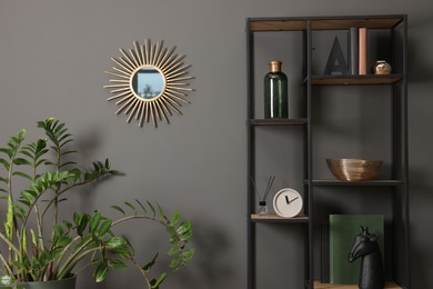 Photo of Shelving unit with decor near grey wall and mirror indoors