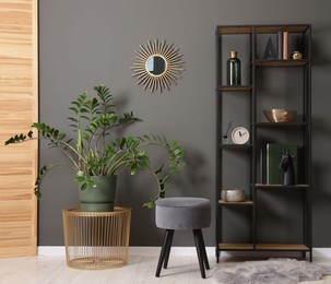 Photo of Shelving unit with decor, stool and folding screen near grey wall indoors