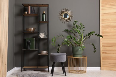 Photo of Shelving unit with decor, stool and folding screen near grey wall indoors