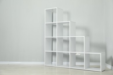 Photo of Empty shelving unit near light grey wall indoors, space for text