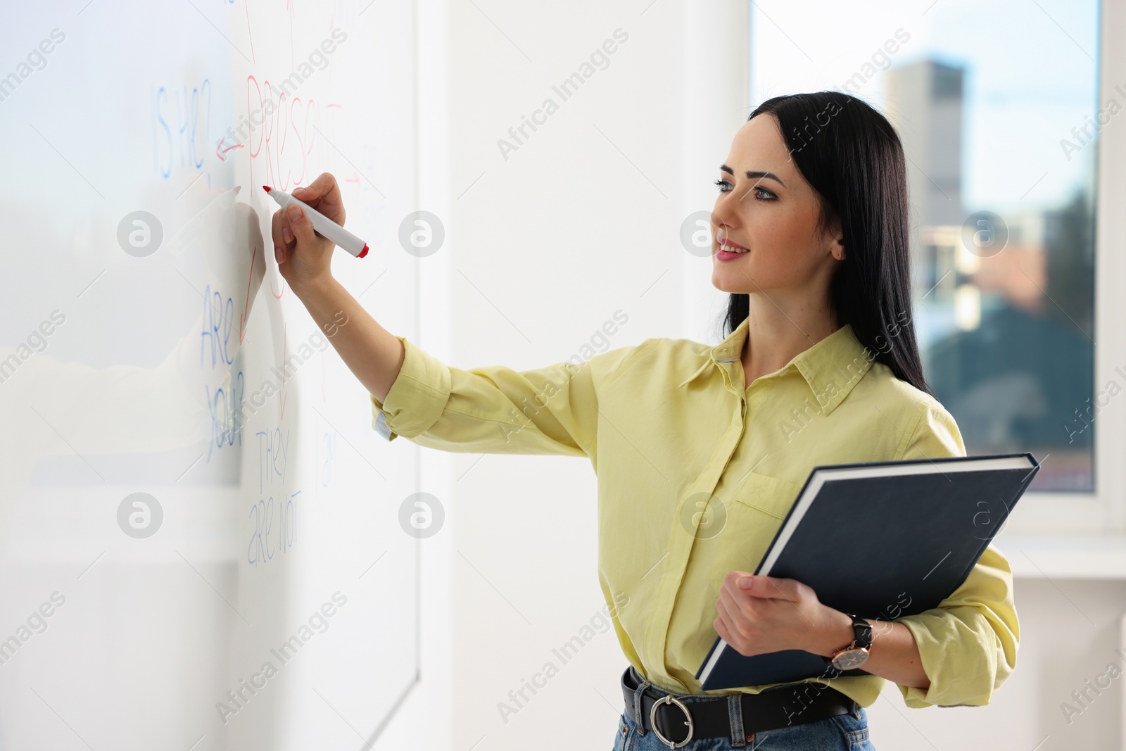 Photo of English teacher writing on whiteboard in classroom