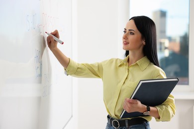 Photo of English teacher writing on whiteboard in classroom