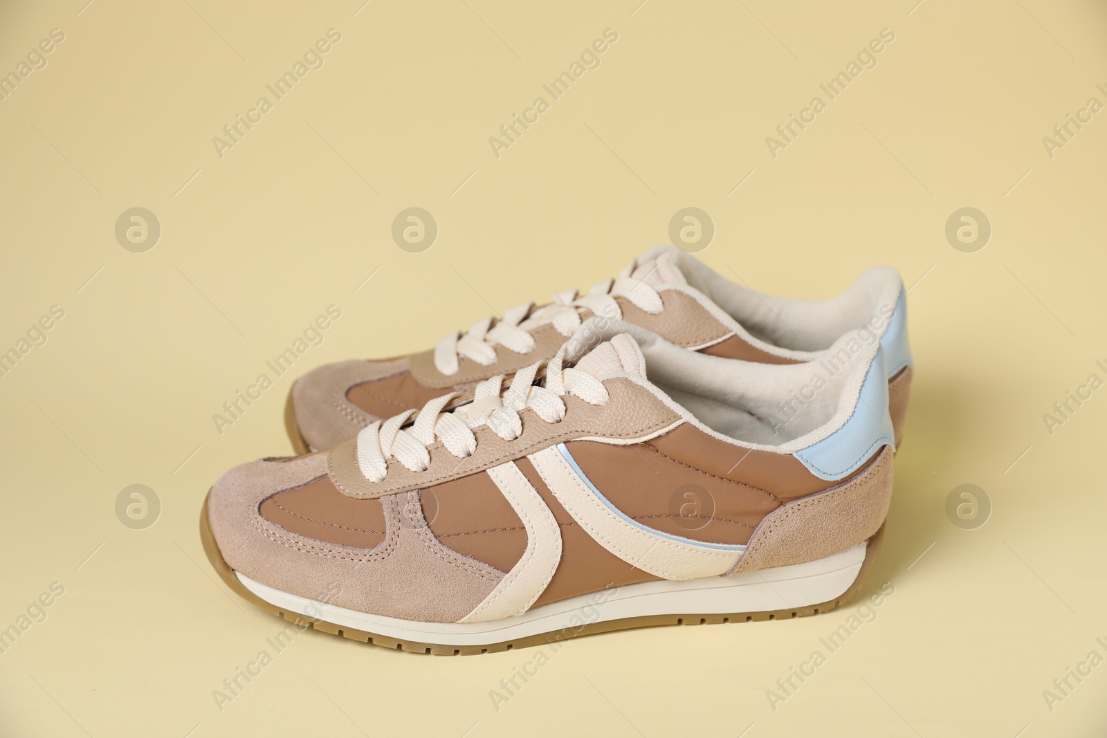 Photo of Pair of stylish sneakers on beige background. Casual shoes