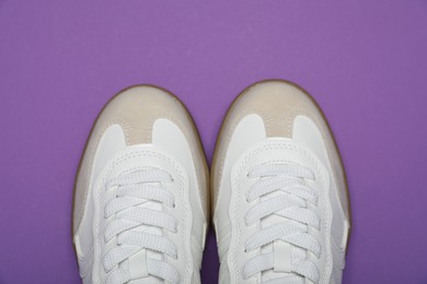 Photo of Pair of stylish sneakers on purple background, flat lay. Casual shoes