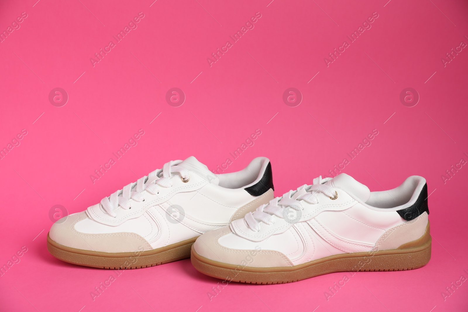 Photo of Pair of stylish sneakers on pink background. Casual shoes