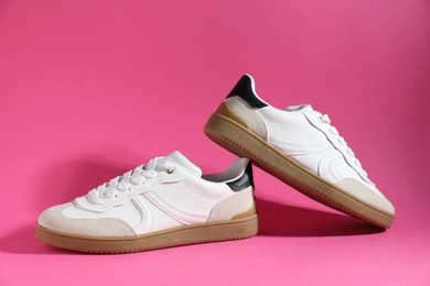 Photo of Pair of stylish sneakers on pink background. Casual shoes