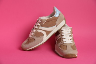 Photo of Pair of stylish sneakers on pink background. Casual shoes