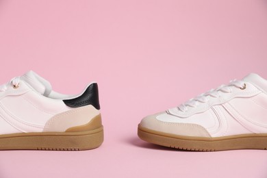 Photo of Pair of stylish sneakers on pale pink background, closeup. Casual shoes