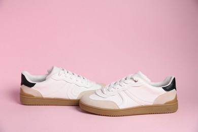 Pair of stylish sneakers on pale pink background. Casual shoes